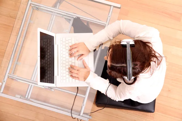 Mujer con un portátil y auriculares — Foto de Stock