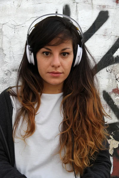 Chica escuchando música mientras se apoya en una pared —  Fotos de Stock