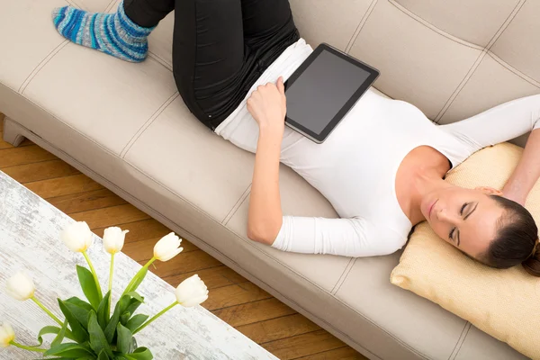 Jeune femme avec une tablette PC sur le canapé — Photo