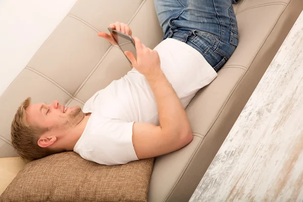 Young man with a Tablet PC on the Sofa — Stock Photo, Image