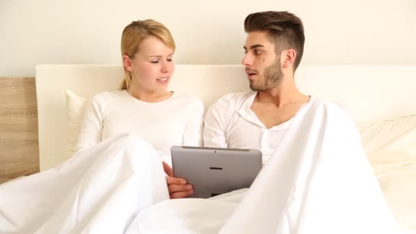 Νεαρό ζευγάρι με ένα tablet pc στο κρεβάτι — Αρχείο Βίντεο