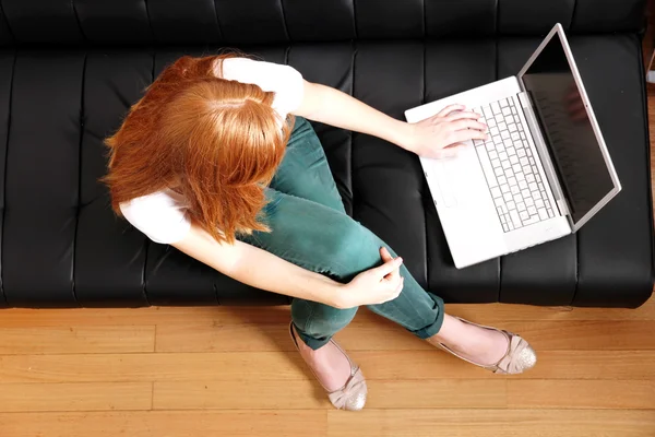 Chica pelirroja joven con un ordenador portátil — Foto de Stock