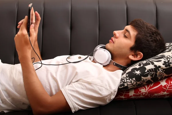 Young man with a Tablet PC and Headphones on the Sofa — Stock Photo, Image