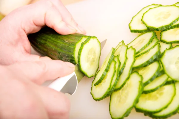 Woman cutting cucumber Stock Image