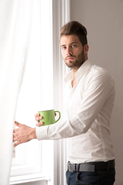 Ein junger Mann steht am Fenster — Stockfoto