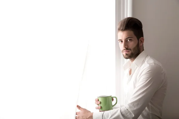 Een jonge man die op het venster — Stockfoto