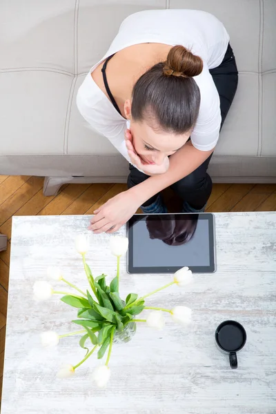 Giovane donna con un Tablet PC sul divano — Foto Stock