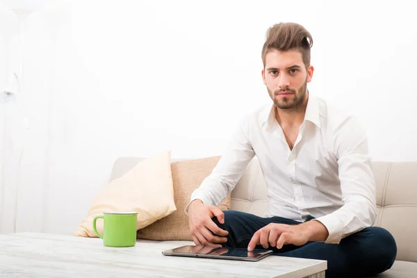 Jovem com um Tablet PC no sofá — Fotografia de Stock