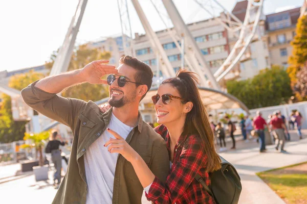 Un couple de voyageurs regardant une grande roue — Photo