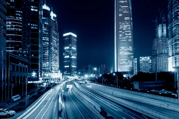 Sentieri luminosi sulla strada con edificio moderno — Foto Stock