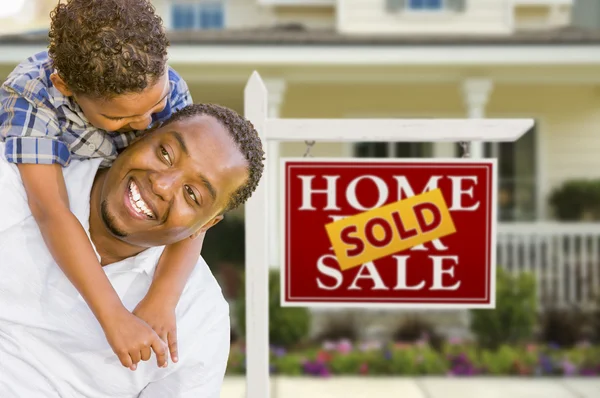 Padre e hijo de raza mixta frente a la firma inmobiliaria y la casa —  Fotos de Stock