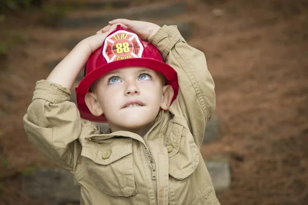 Очаровательный мальчик в шапке пожарного, играющий на улице — стоковое фото