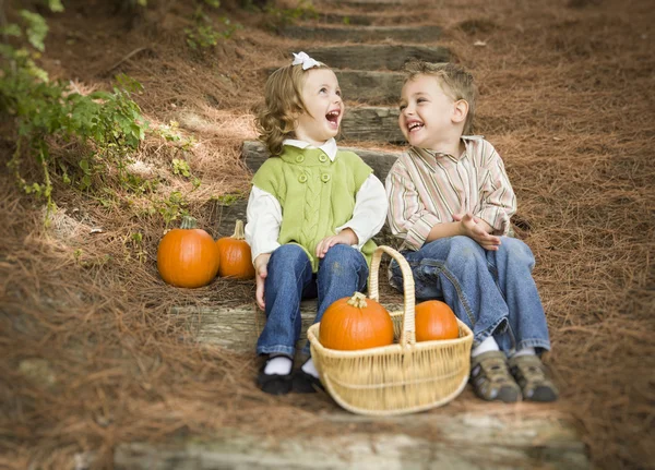 Broer en zus kinderen zittend op houten stappen met pompoenen — Stockfoto