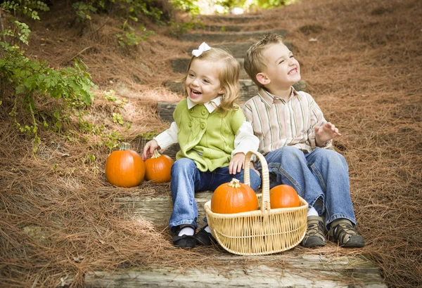 Fratello e sorella bambini seduti su gradini di legno con zucche — Foto Stock