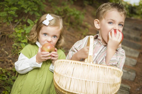 Crianças adoráveis comendo maçãs vermelhas fora — Fotografia de Stock