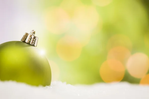 Green Christmas Ornaments on Snow Over an Abstract Background — Stock Photo, Image