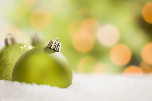 Green Christmas Ornaments on Snow Over an Abstract Background — Stock Photo, Image