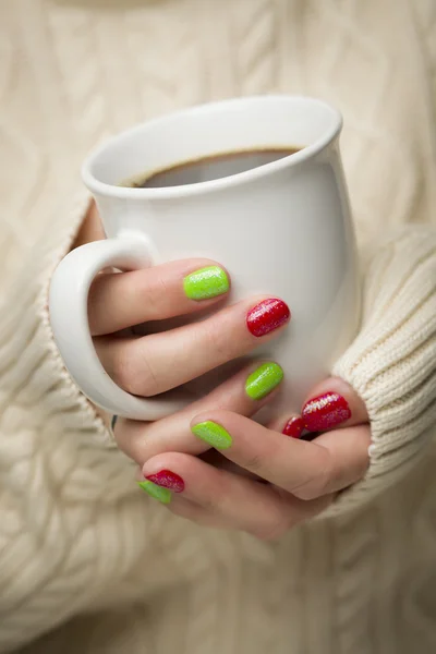 Mulher com unhas vermelhas e verdes polonês segurando xícara de café — Fotografia de Stock