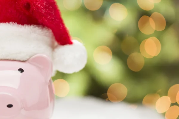 Rosa Sparschwein mit Weihnachtsmütze auf Schneeflocken — Stockfoto