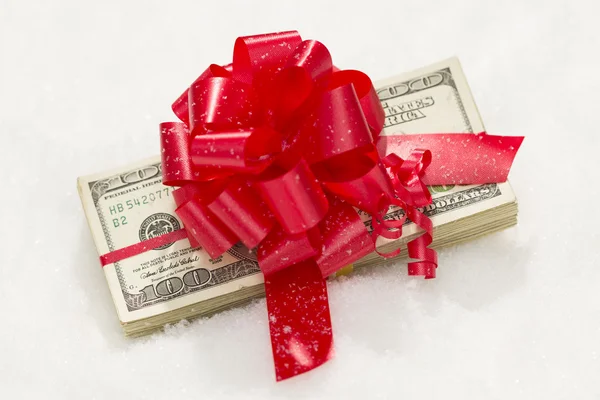 Stapel van honderd dollar bills met rood lint op sneeuw — Stockfoto