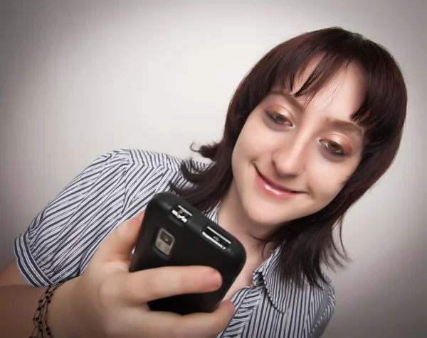 Lachende brunette vrouw met behulp van mobiele telefoon — Stockfoto