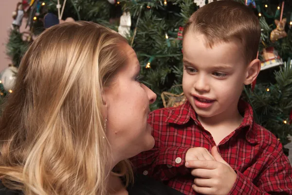 Entzückender Sohn im Gespräch mit Mama vor dem Weihnachtsbaum — Stockfoto