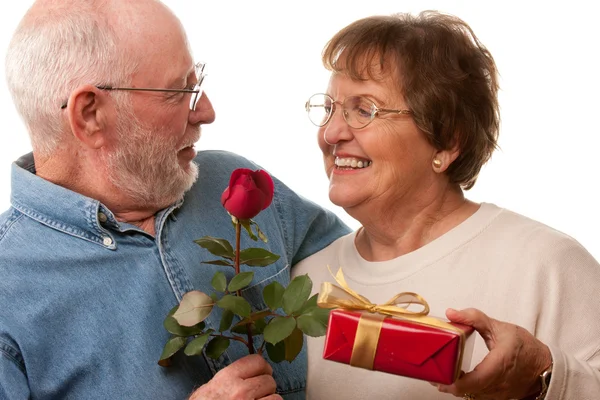 Gelukkig senior koppel met cadeau en rode rose — Stockfoto