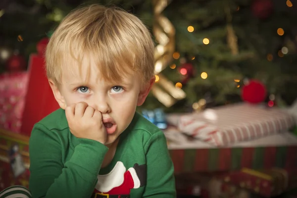 Huysuz çocuk Noel ağacının yanında oturan — Stok fotoğraf