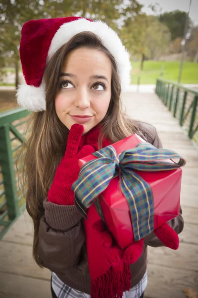 Hübsche Frau mit Weihnachtsmütze und umwickeltem Geschenk — Stockfoto