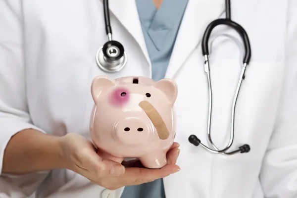 Médico segurando Piggy Bank com olho ferido e bandagem — Fotografia de Stock