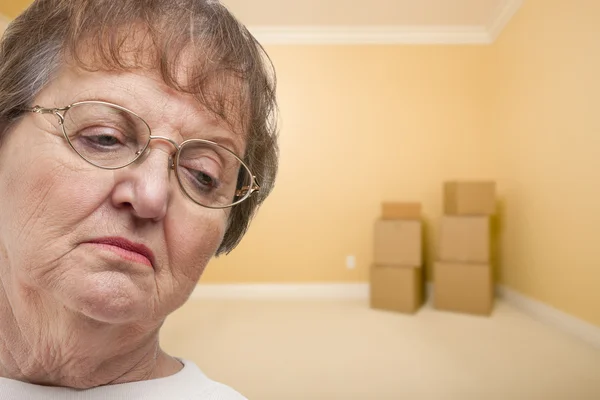 Triste mujer mayor en habitación vacía con cajas — Foto de Stock