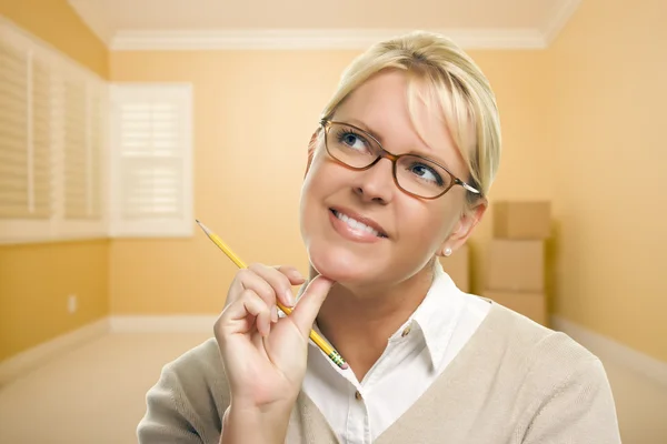 Mujer soñando despierto con lápiz en habitación vacía y cajas —  Fotos de Stock