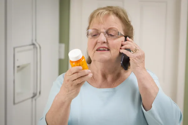 Mulher adulta sênior no telefone celular segurando garrafa de prescrição — Fotografia de Stock