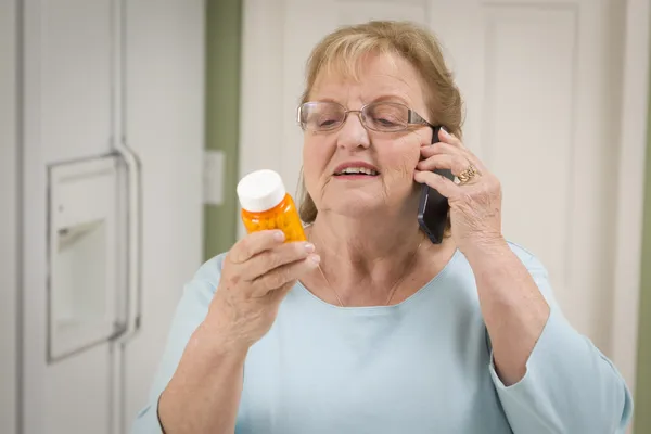 Femme adulte âgée sur téléphone cellulaire tenant bouteille d'ordonnance — Photo