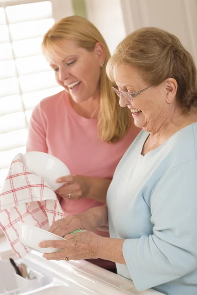 Senior volwassen vrouw en jonge dochter praten in keuken — Stockfoto