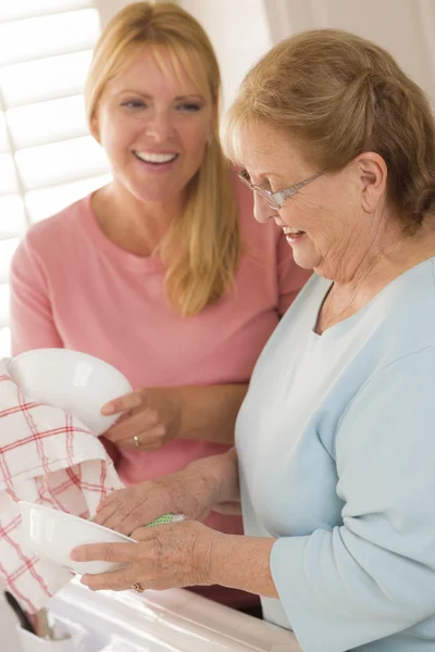 Senior volwassen vrouw en jonge dochter praten in keuken — Stockfoto