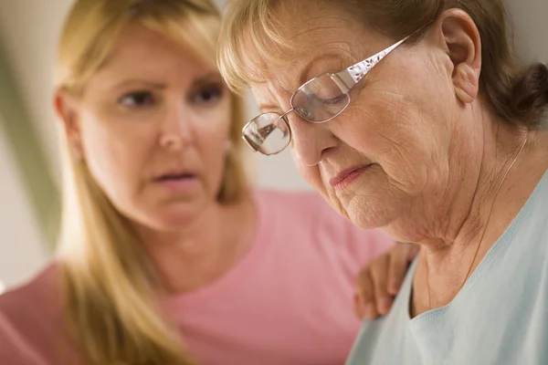 Junge Frau tröstet erwachsene Seniorin — Stockfoto