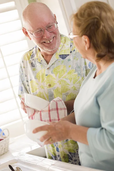 Pareja de adultos mayores lavando platos juntos dentro de la cocina — Foto de Stock