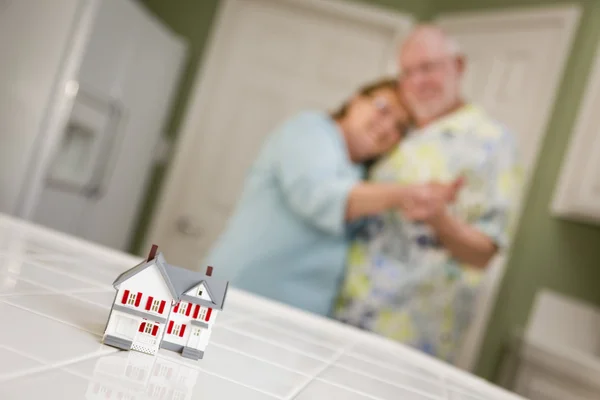Senior adult paar starend over kleine model thuis op teller — Stockfoto
