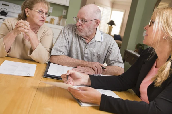 Pareja de adultos mayores revisando documentos en su casa con el agente — Foto de Stock
