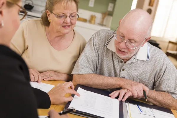 Senior vuxna par som går över papper i sitt hem med agent — Stockfoto