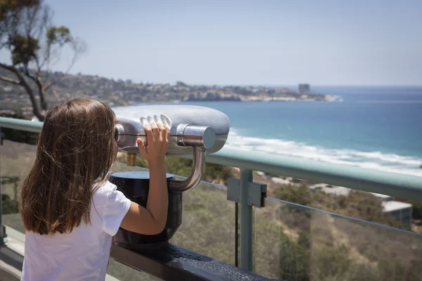 Jong meisje kijkt uit over de Stille Oceaan met telescoop — Stockfoto
