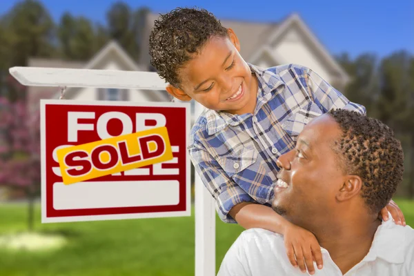 Padre e hijo de raza mixta frente a la firma inmobiliaria y la casa — Foto de Stock