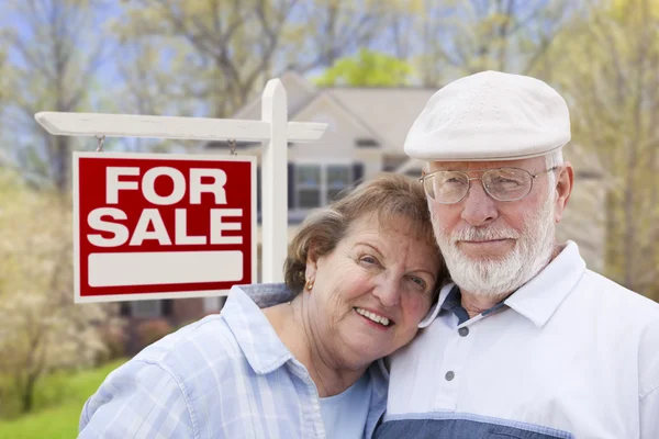 Heureux couple de personnes âgées avant de à vendre signe et maison — Photo