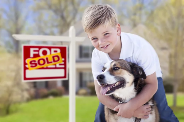 Kleiner Junge und sein Hund vor verkauftem Schild und Haus — Stockfoto