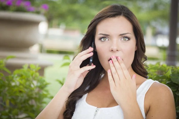 Chockade unga vuxna kvinnliga talar i mobiltelefon utomhus — Stockfoto