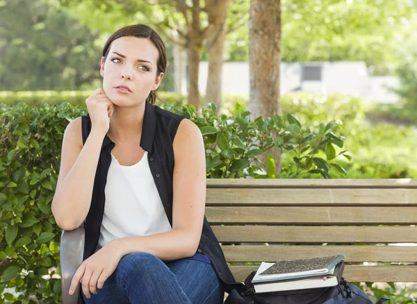 Szomorú fiatal felnőtt nő ül a padon mellette könyv — Stock Fotó