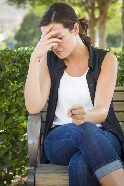 Upprörda ung kvinna sitter ensam på bänk — Stockfoto