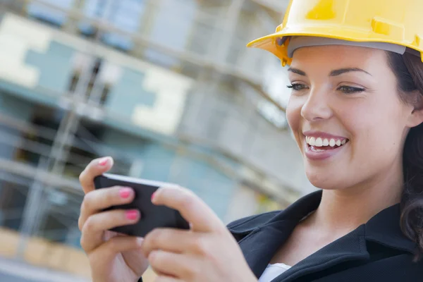 Bauunternehmerin trägt harten Hut vor Ort SMS mit Telefon — Stockfoto