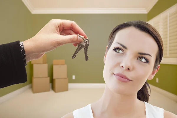 Joven mujer siendo entregada llaves en habitación vacía con cajas — Foto de Stock